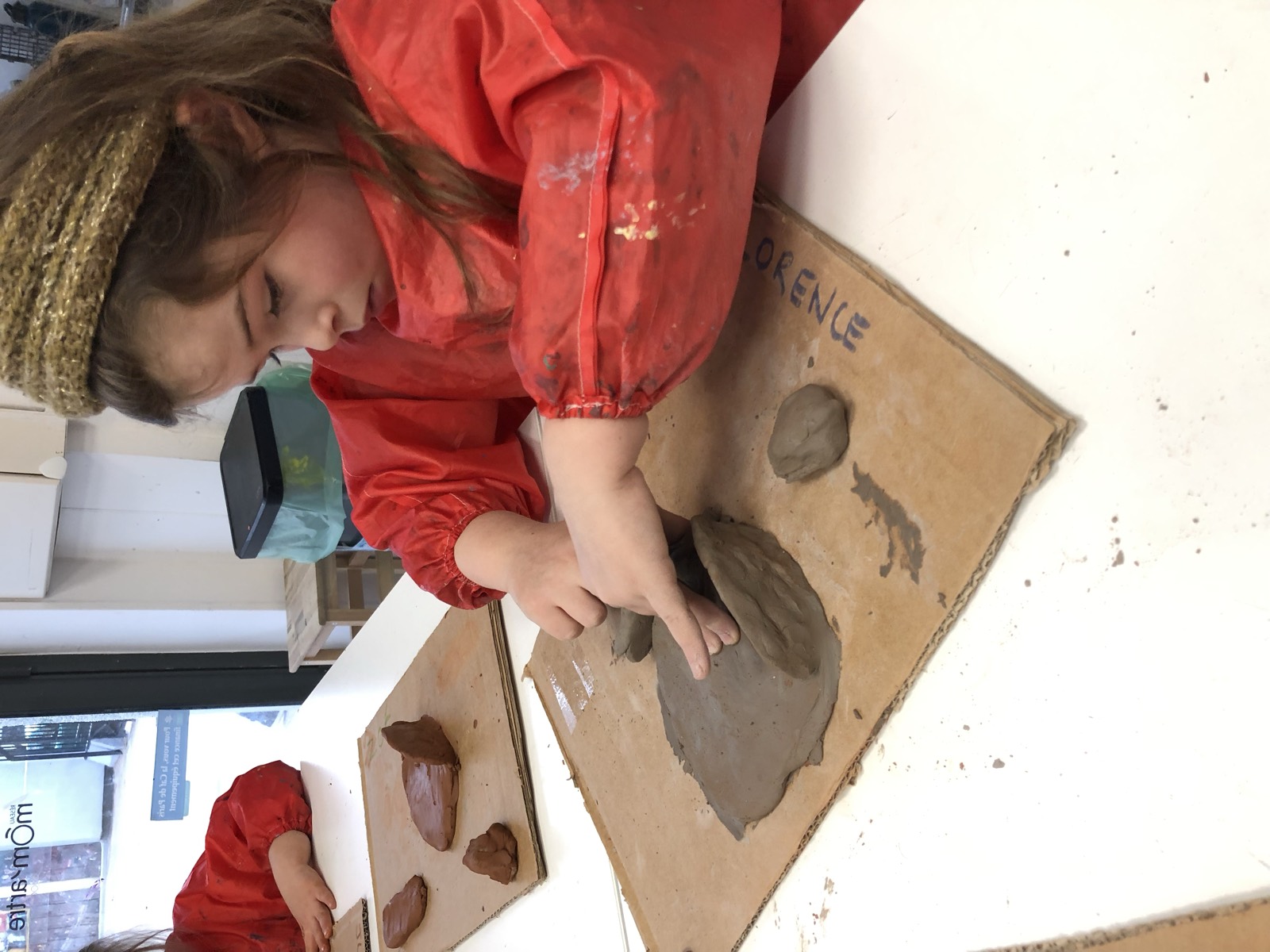Une enfant travaille l'argile sur une planche